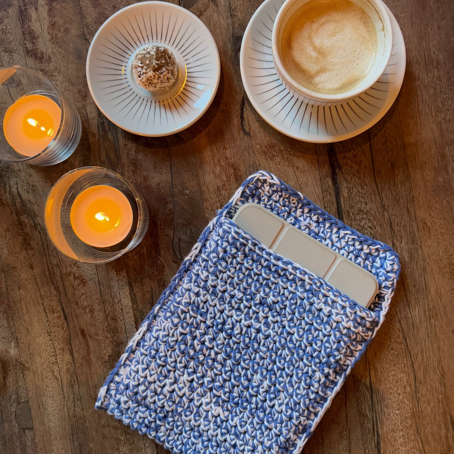 DIY-kit Smooth Sleeve i färgen blå/vit placerat på ett bord med fika och tända ljus.